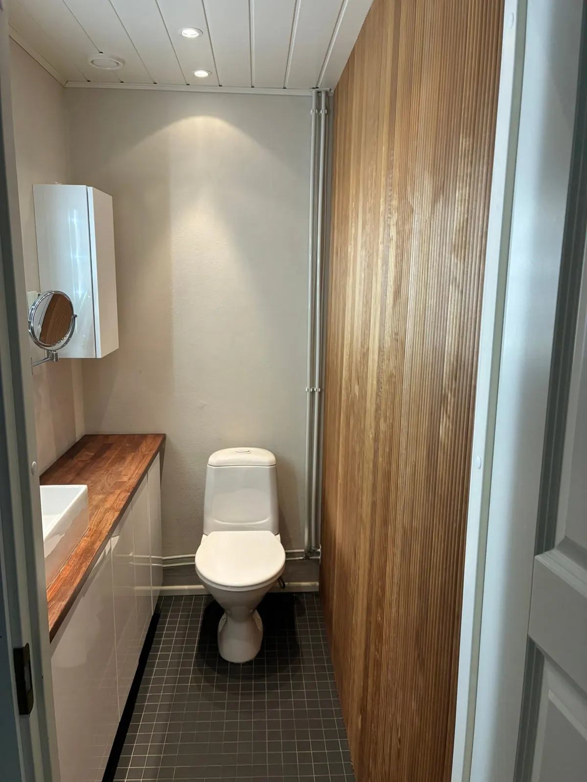 WC, jossa puupaneeliseinä ja puinen taso